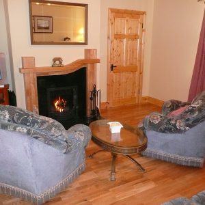 Skelligs House, Living Room with Couch, Cairs and a cosy Fire. Rent an Irish Cottage with Sea View along the Wild Atlantic Way in Kerry from www.fir-darrig.net. Rent a Holiday Home with Seaview in Ireland along the Ring of Kerry.