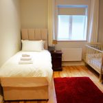 Ein Einzelbett und ein Babybett in Schlafzimmer zwei im Erdgeschoss von Ferienhaus Castle View in Glenbeigh in Kerry, Irland.